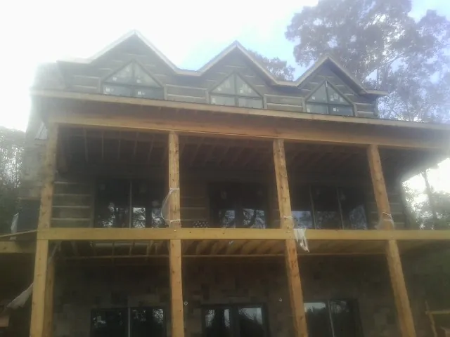 Dormers and porch framing on a large log home under construction — Roof Coating work by our crew in Colfax